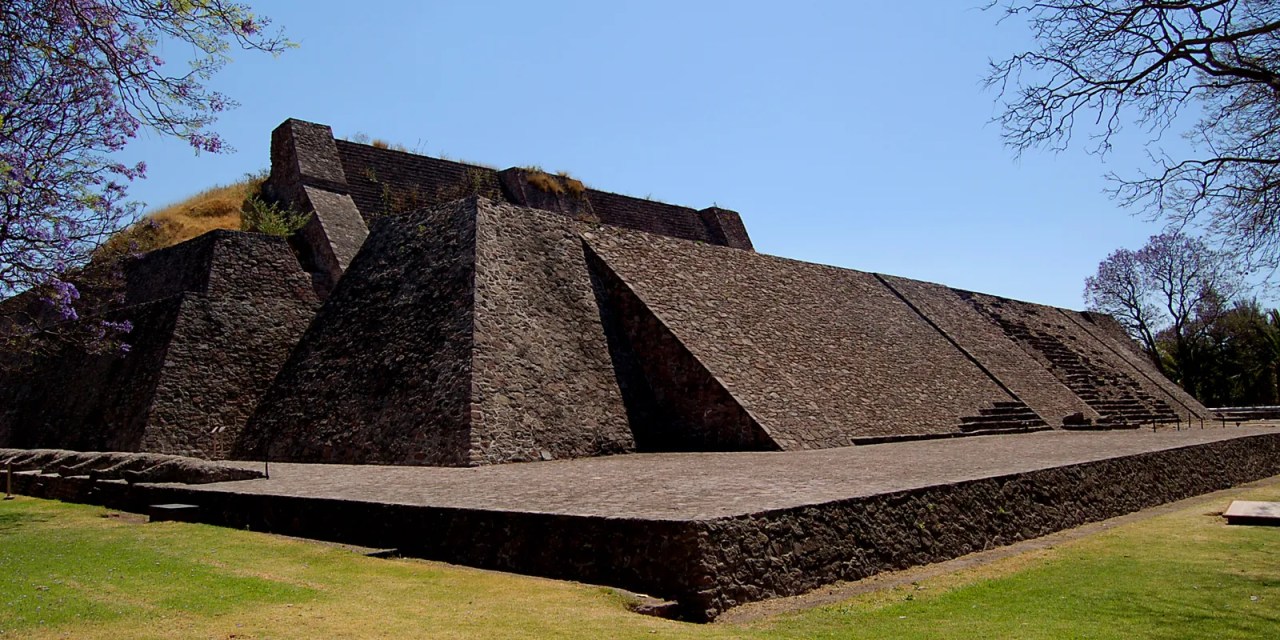 Vista de una estructura moderna de piedra con rampas y escaleras bajo un cielo azul despejado.