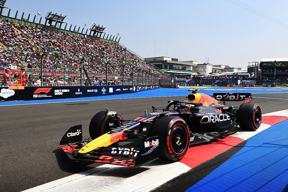 A Formula 1 car from the Red Bull Racing team navigating a corner on the track, with a packed grandstand of fans in the background during a race.