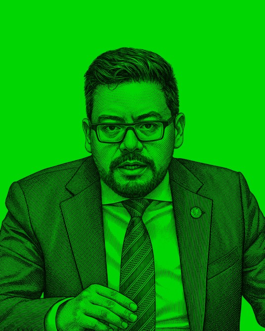 A portrait of a man in a suit and tie with glasses, set against a bright green background, conveying a serious expression.
