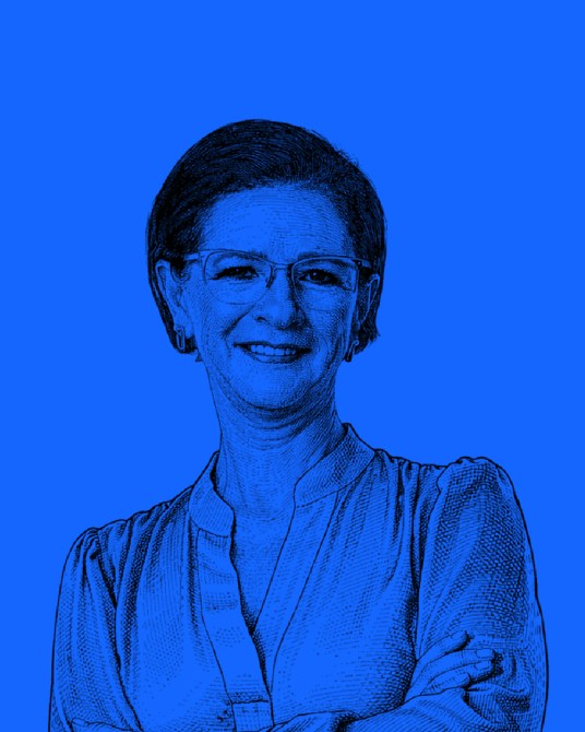 Retrato de una mujer sonriendo con brazos cruzados, fondo azul.