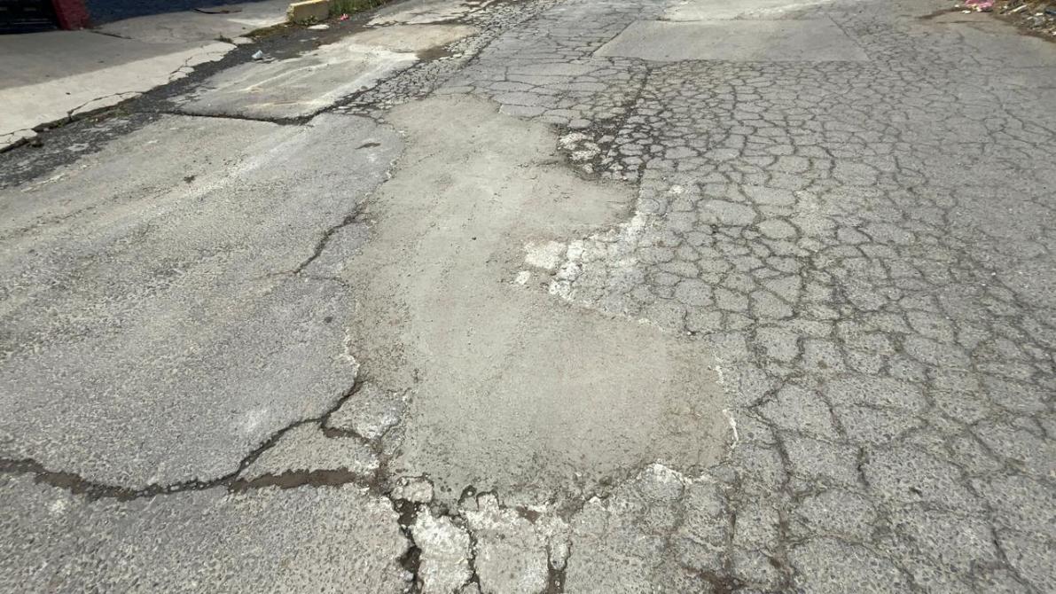 A close-up view of a damaged and cracked asphalt road surface.