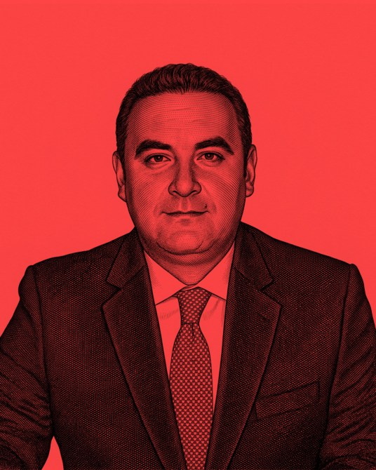 Retrato de un hombre con traje y corbata, de frente, sobre un fondo rojo.