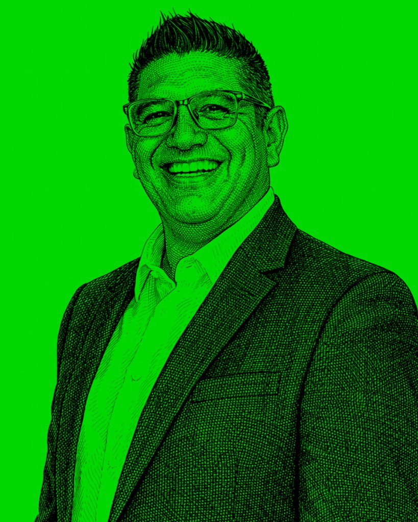 Retrato de una persona sonriendo, con chaqueta y camisa blanca, sobre un fondo verde brillante.