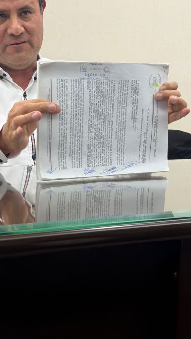 A person holding a document with text, displaying the content and signatures, in an office setting.