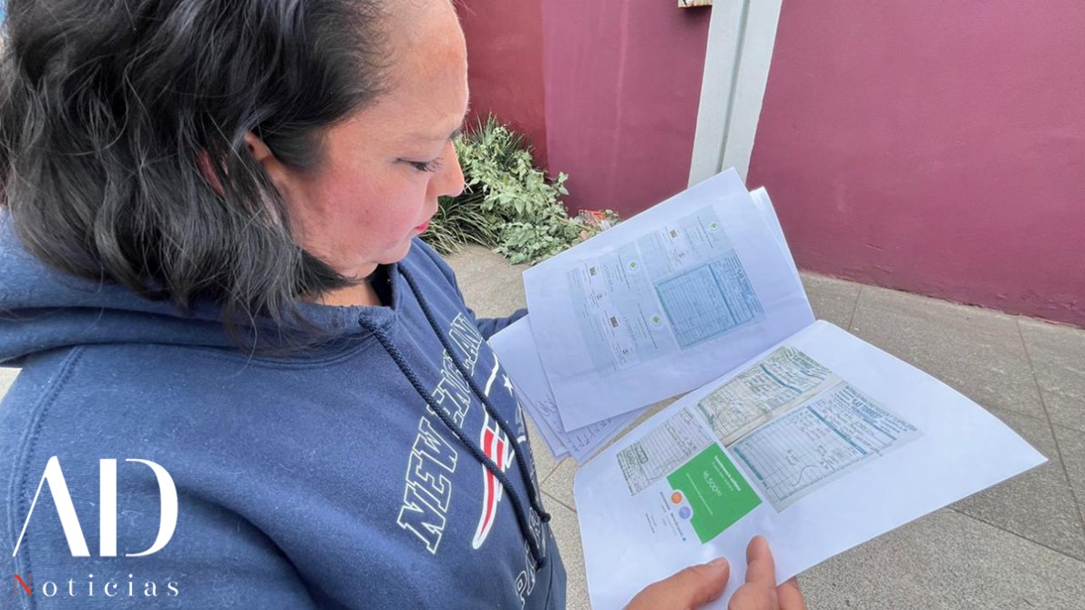 Una mujer revisando documentos en papel, mostrando formularios y datos en hojas impresas, mientras se encuentra de pie en una vía pública.