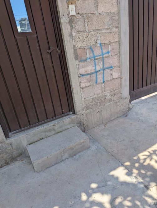 Puerta de madera con un pequeño escalón y un dibujo azul en la pared de ladrillos junto a ella.