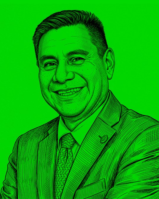 Retrato de un hombre sonriendo, vestido con un traje y corbata, sobre un fondo verde brillante.