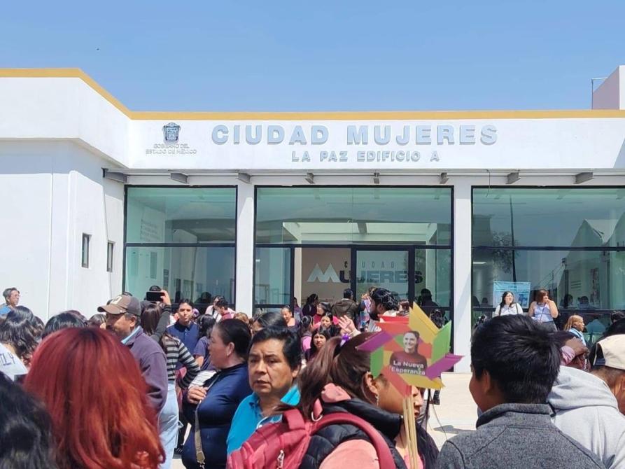 Exterior del edificio Ciudad Mujeres en La Paz, con una gran multitud de personas reunidas frente a la entrada.