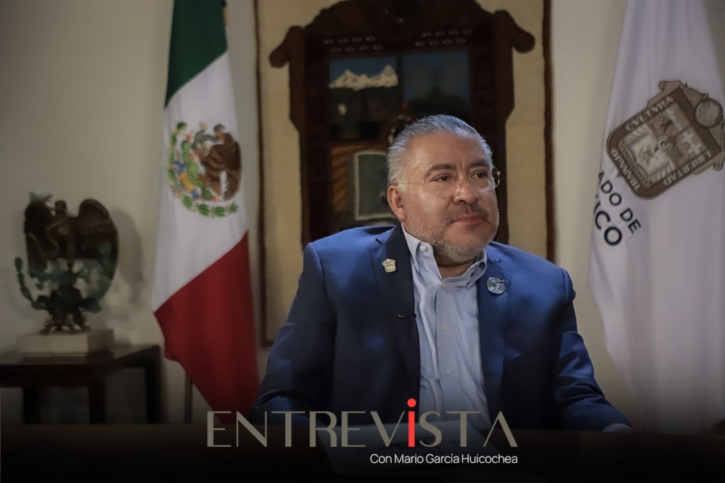 Entrevista con Mario García Huicochea en un entorno que muestra la bandera de México y un mural en el fondo.