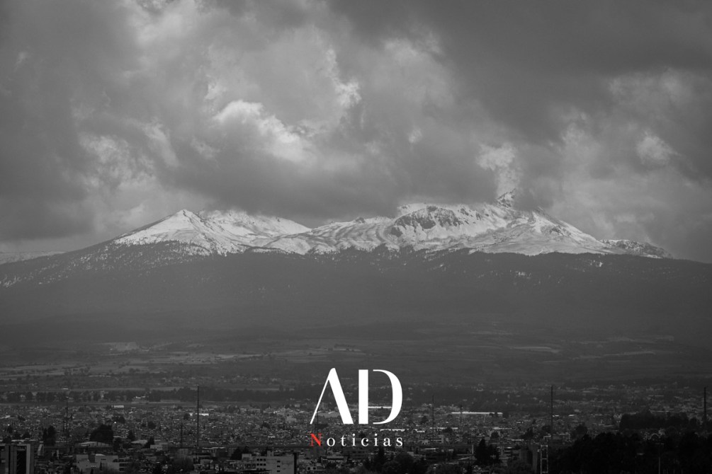 Vista panorámica de montañas nevadas bajo un cielo nublado en blanco y negro.
