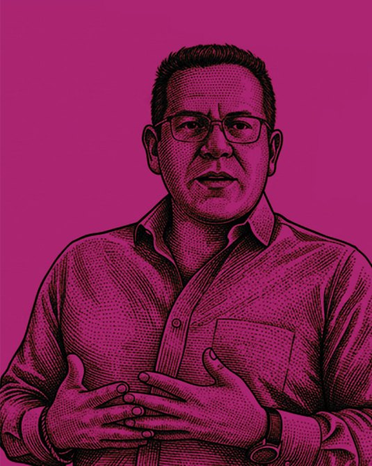 Retrato de un hombre con gafas y camisa de botones, gesticulando con las manos ante un fondo rosa.