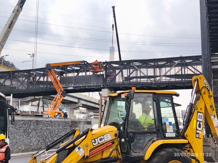 Obra en construcción con maquinaria pesada y trabajadores, mostrando un puente en proceso de montaje.