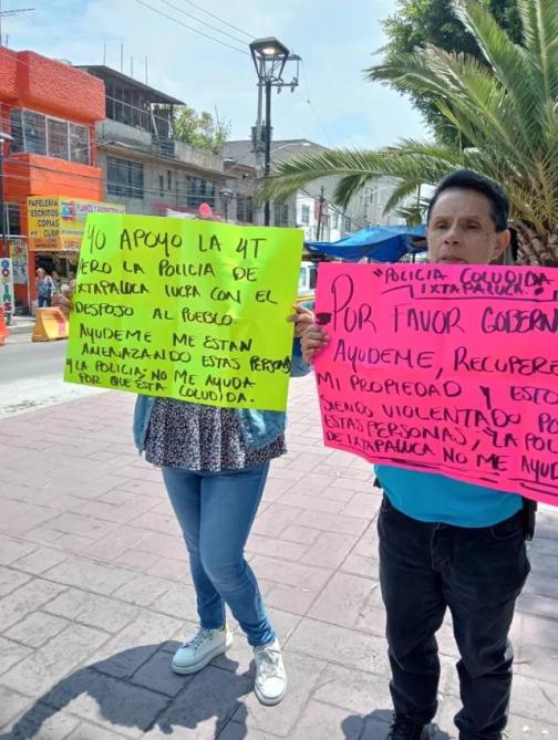 Manifestantes sosteniendo carteles coloridos en la calle, expresando su apoyo a la 4T y solicitando ayuda debido a problemas con la policía de Ixtapaluca.