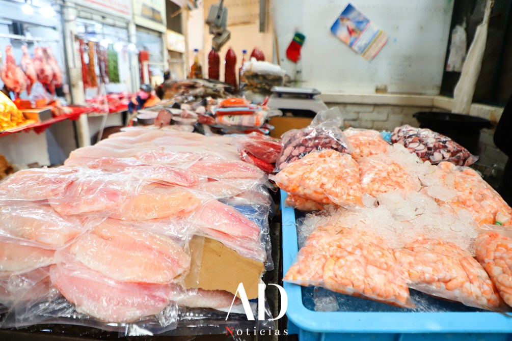 Mesa de mercado con filetes de pescado y mariscos en hielo.