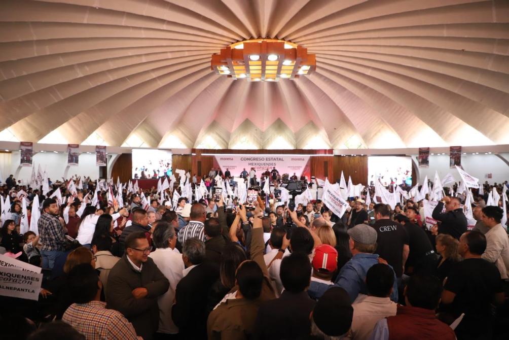 Congreso estatal con una multitud de personas sosteniendo banderas y pancartas en un ambiente de reunión política.