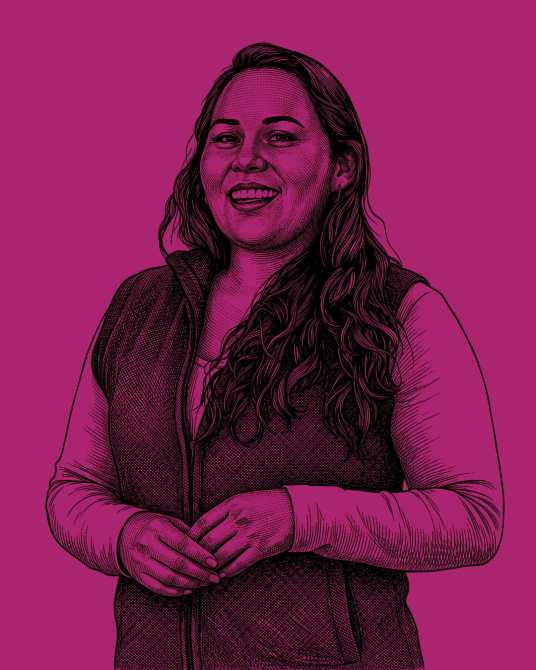 Retrato de una mujer sonriente de cabello largo y ondulado, usando un chaleco oscuro sobre una camisa clara, contra un fondo rosa.