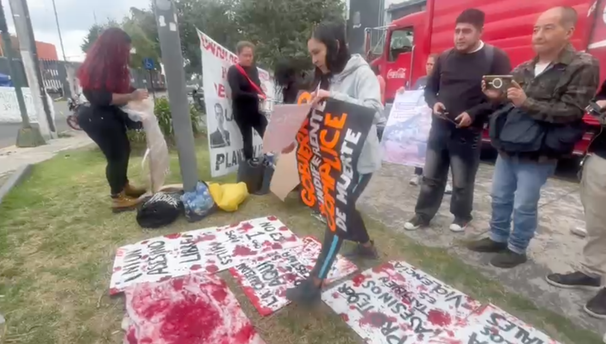Un grupo de personas participando en una manifestación, sosteniendo pancartas y carteles con mensajes en un espacio público.