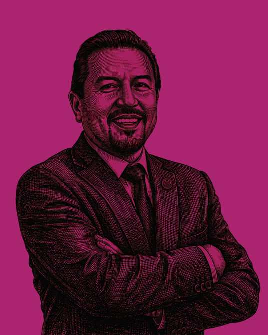 Retrato de un hombre sonriente con brazos cruzados, vestido con traje oscuro sobre un fondo rosa.
