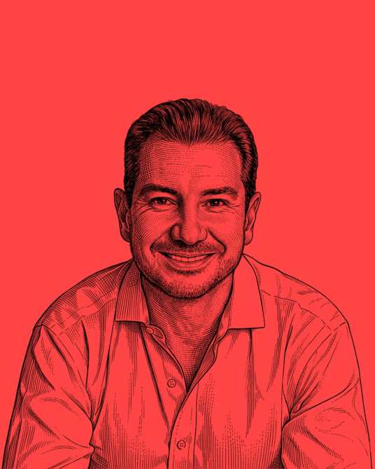 Retrato de un hombre sonriente con camisa clara, frente a un fondo rojo.