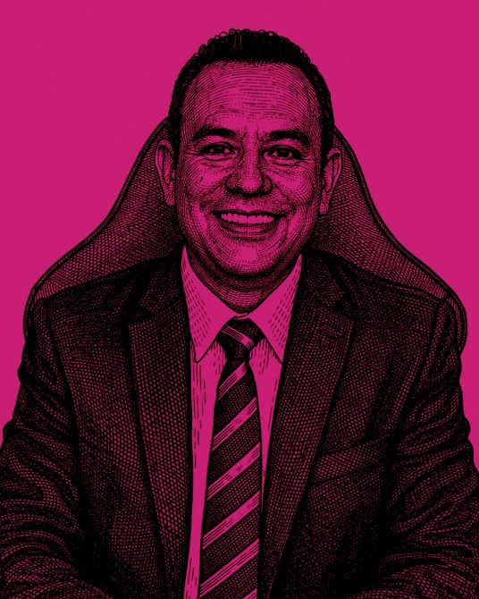 Retrato en tonos de rosa de un hombre sonriente con traje y corbata, sentado en una silla de oficina.