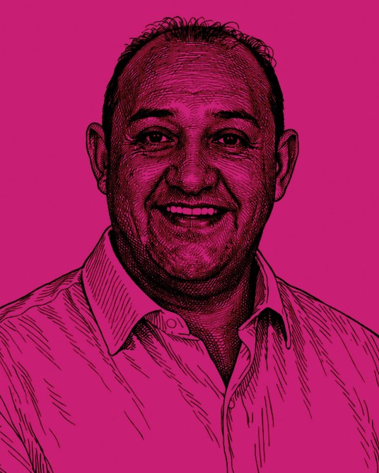 Retrato de una persona sonriendo con fondo rosa.