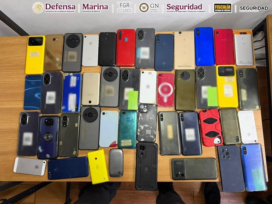 Imagen que muestra una variedad de teléfonos móviles de diferentes colores y modelos dispuestos sobre una mesa de madera.