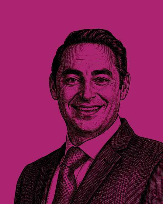 Retrato de un hombre sonriente, con traje y corbata, sobre un fondo púrpura.