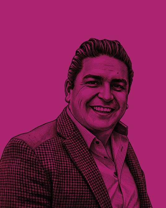 Retrato de un hombre sonriendo, con cabello ondulado y usando un traje, sobre un fondo de color púrpura.