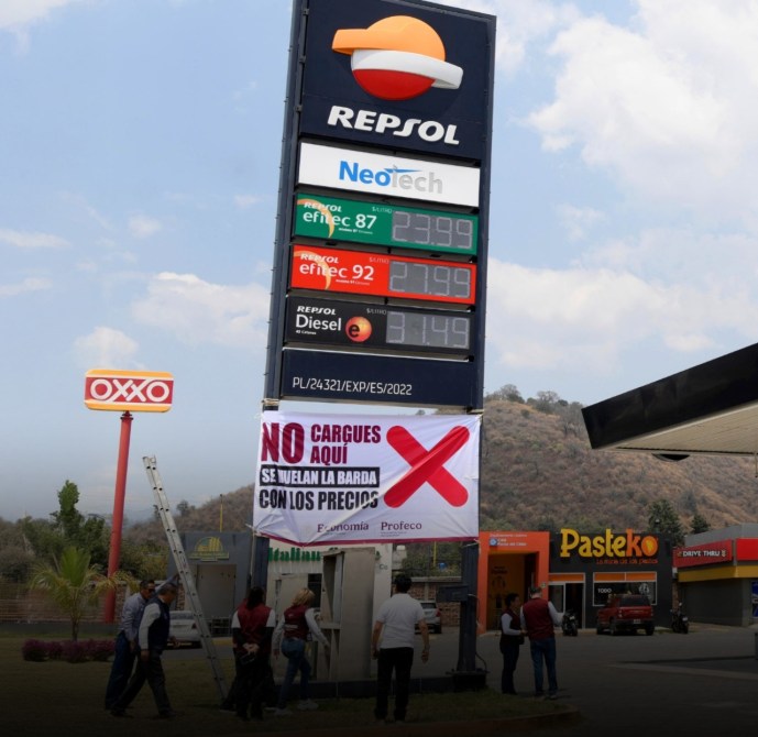 Panel de precios de gasolinería Repsol con precios de gasolina efec 87, efec 92 y diesel. Banner que dice 'NO CARGUES AQUÍ SE VUELAN LA BARDA CON LOS PRECIOS'.
