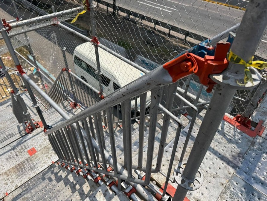 Escalera de metal en una construcción con barandales y cerca de seguridad, vista desde arriba.