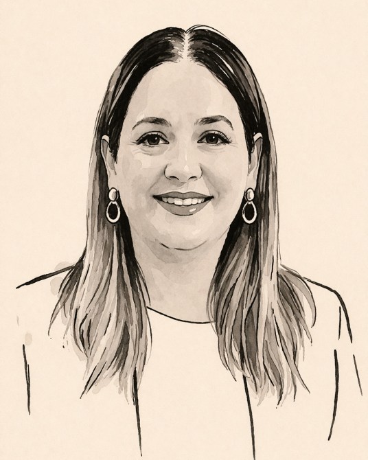 Retrato en blanco y negro de una mujer sonriendo, con cabello largo y lacio y pendientes grandes. Lleva una blusa clara.