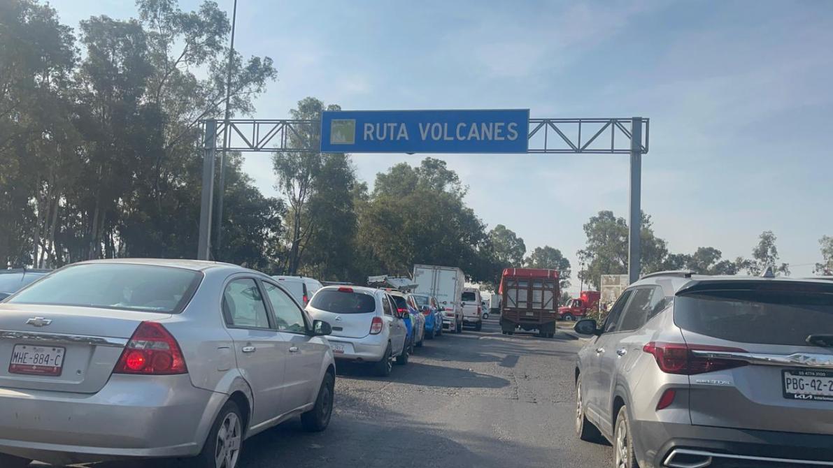 Señal de tráfico que indica la 'Ruta Volcanes' en una carretera con varios vehículos detenidos.