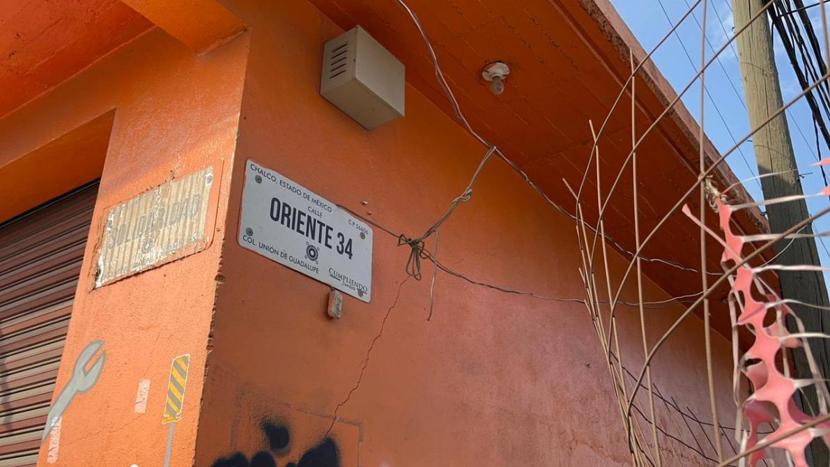Vista de un edificio con una pared pintada de naranja y un letrero de calle que dice 'ORIENTE 34' en Chalco, Estado de México.