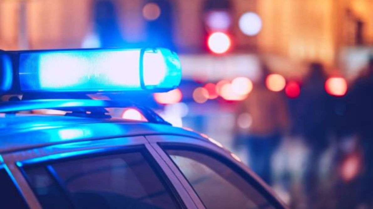 Luz azul en el techo de un coche de policía con un fondo de luces borrosas de la ciudad de noche.