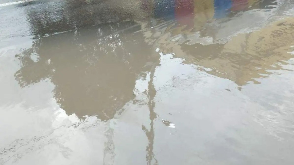 Reflejo en un charco de agua en la calle, con colores difusos y una superficie ligeramente ondulada.
