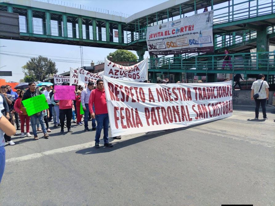 Manifestación en la calle con personas sosteniendo pancartas que reclaman respeto a la Feria Patronal San Cristóbal.