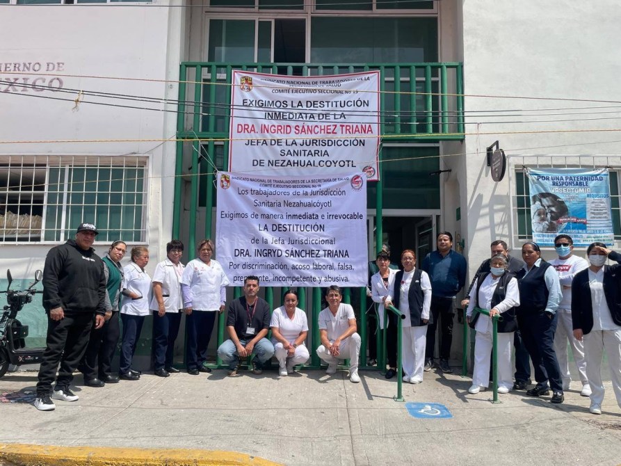 Grupo de trabajadores de la Jurisdicción Sanitaria de Nezahualcóyotl protestando frente a su edificio, sosteniendo pancartas que exigen la destitución de la Dra. Ingrid Sánchez Triana.