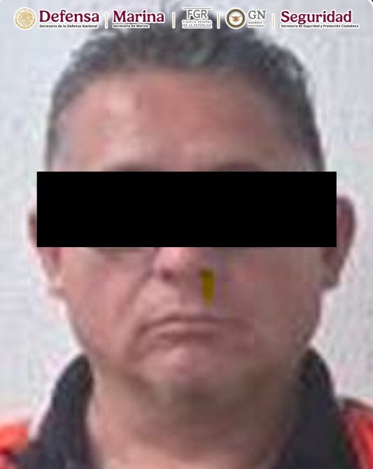 Retrato en primer plano de un hombre con cabello corto y ojos serios, con un fondo gris claro. La parte superior de la imagen incluye logotipos de instituciones de seguridad.