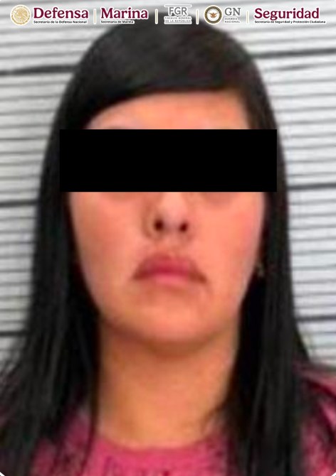 Foto de identificación de una mujer con cabello largo y lacio, frente a una pared de rayas. La mujer tiene un look serio y no se muestra su identidad debido a la censura.