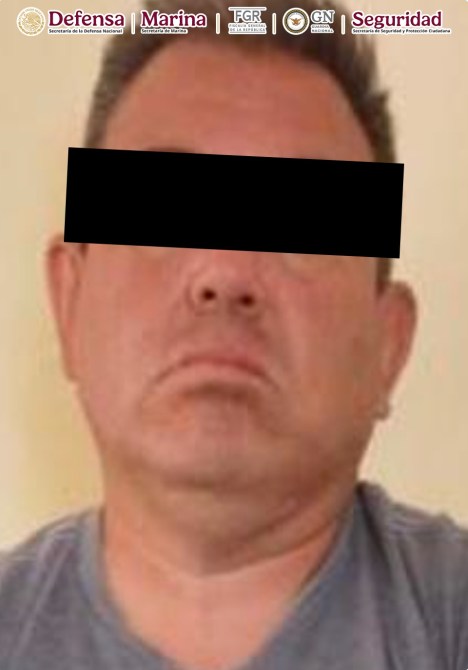 Retrato de un hombre con expresión seria, con el rostro parcialmente cubierto por un bloque negro, sobre un fondo claro.