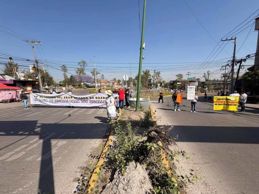 Protesta en una carretera con pancartas que reclaman recursos para el agua en Izcalli. Hay un grupo de personas en la vía, bloqueando el tráfico.