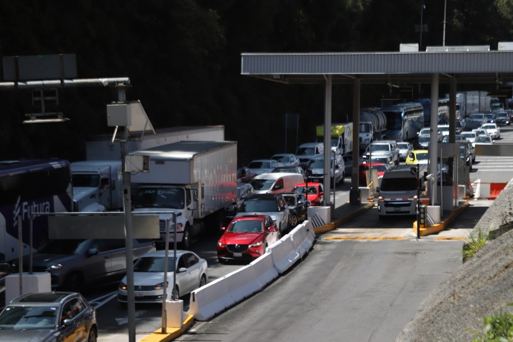 Tráfico en un peaje, con varios vehículos esperando en fila.