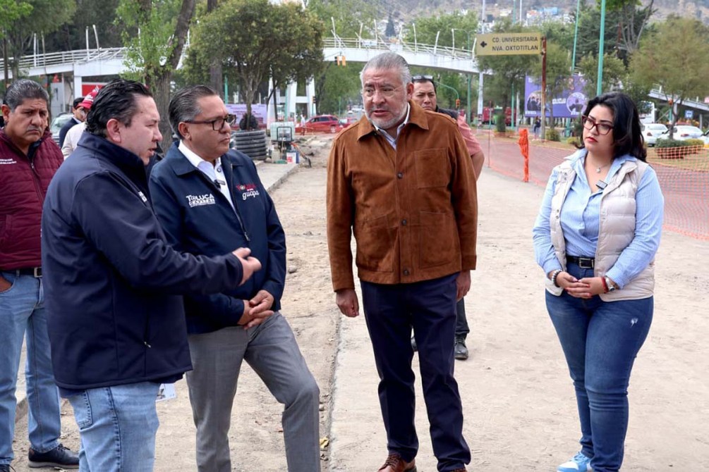 Grupo de personas conversando en una obra en construcción al aire libre, con un ambiente urbano de fondo.
