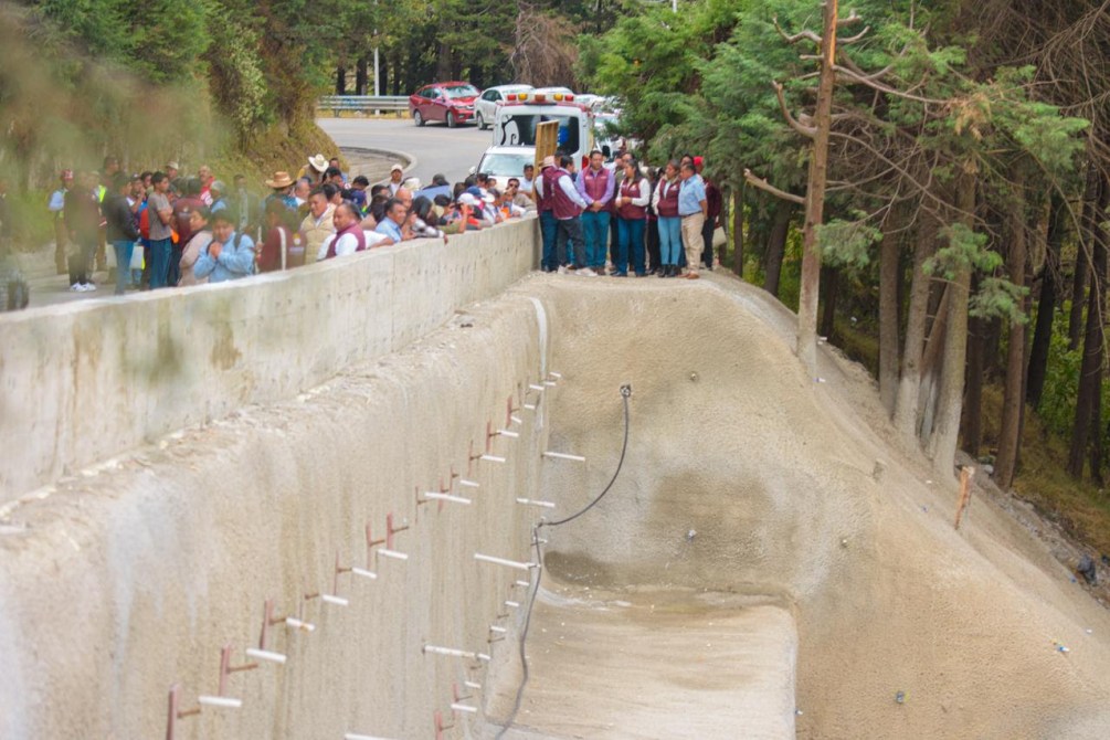 Grupo de personas reunidas junto a una obra de construcción en un área forestal.