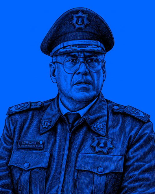 Retrato de un comisario con uniforme policial, usando gafas y gorra, sobre un fondo azul.