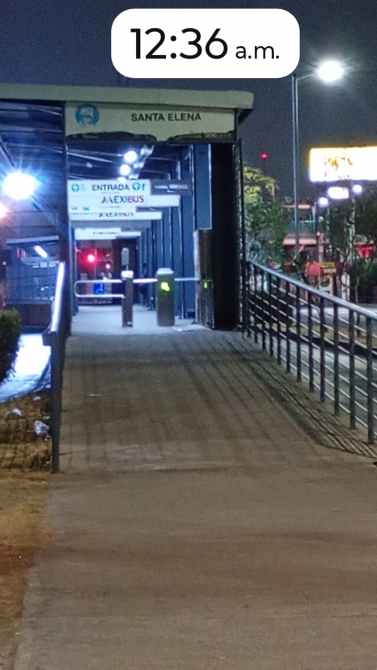 Pasillo iluminado del estacionamiento en la estación de autobuses Santa Elena, con señalización visible y ambiente nocturno.