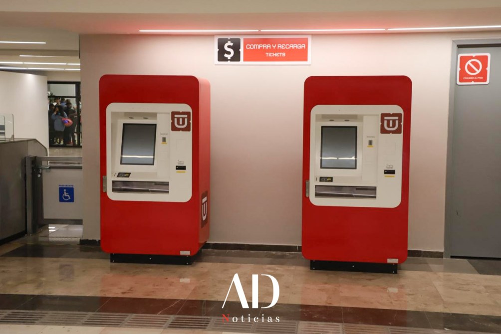 Máquinas expendedoras de boletos en un espacio público, junto a un letrero que dice 'COMPRAR Y RECARGAR'.