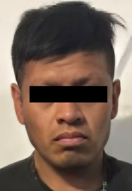 Retrato de un hombre con cabello negro y corto, con una expresión seria, en un fondo claro.