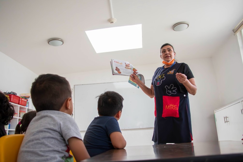 Una maestra presentando un cuento a un grupo de niños en un aula.
