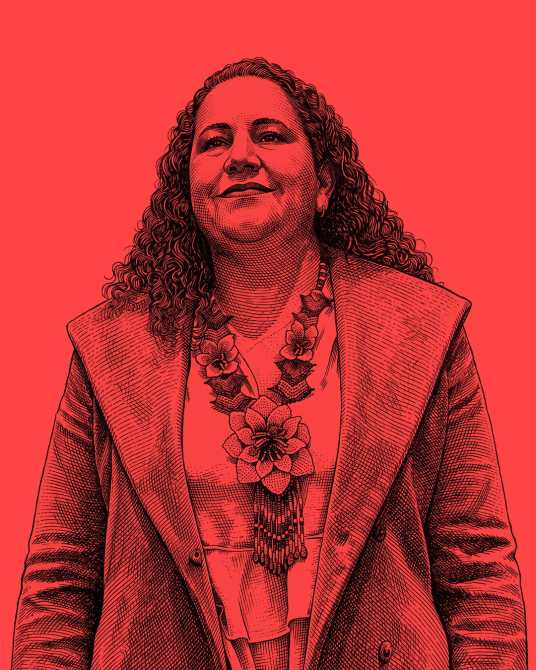 Retrato de mujer con cabello rizado y suelto, usando una chaqueta y un collar decorativo, sobre un fondo rojo.